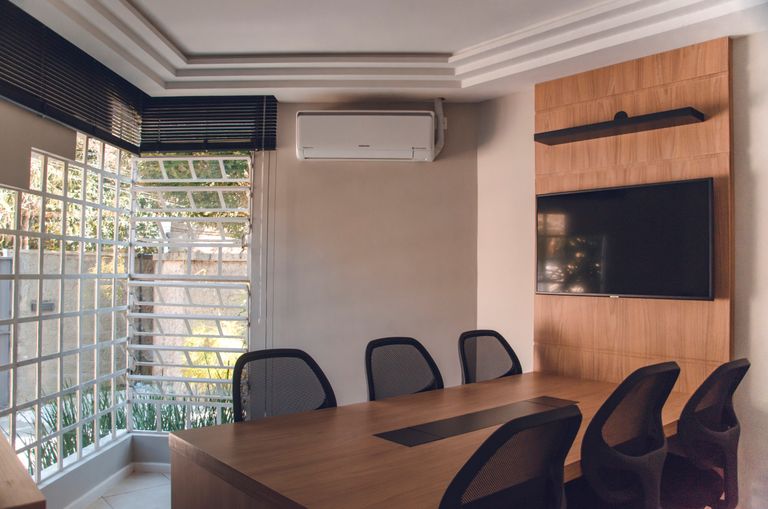 Spacious modern conference room featuring wooden table, chairs, TV, and air conditioning unit.